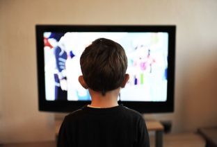 Un jeune garçon regarde un écran de télévision.