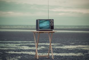 Télévision ancienne posée sur un support en bois.